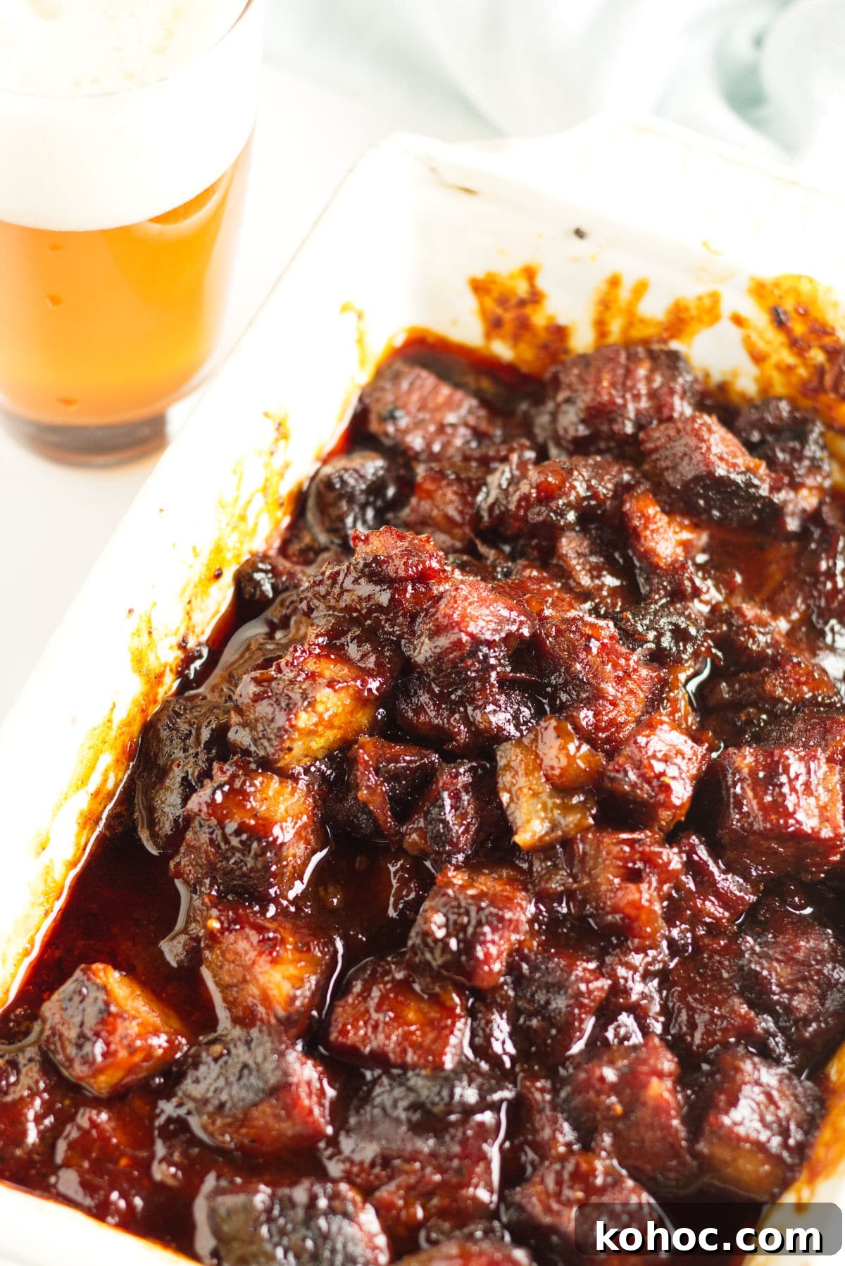 22 Memorial Day Recipes for the Ultimate Backyard BBQ 9 White dish with smoked brisket burnt ends in a kansas city-barbecue sauce with a glass of beer