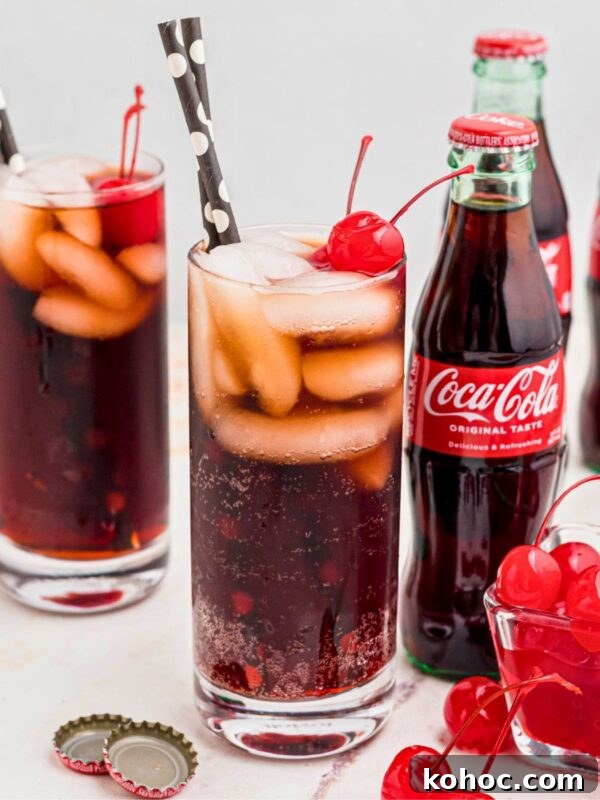 Green Tea Shot Recipe: How to Make the Classic Cocktail 8 Cola and grenadine mixed in a glass filled with ice, and topped with cherries on a marble table.