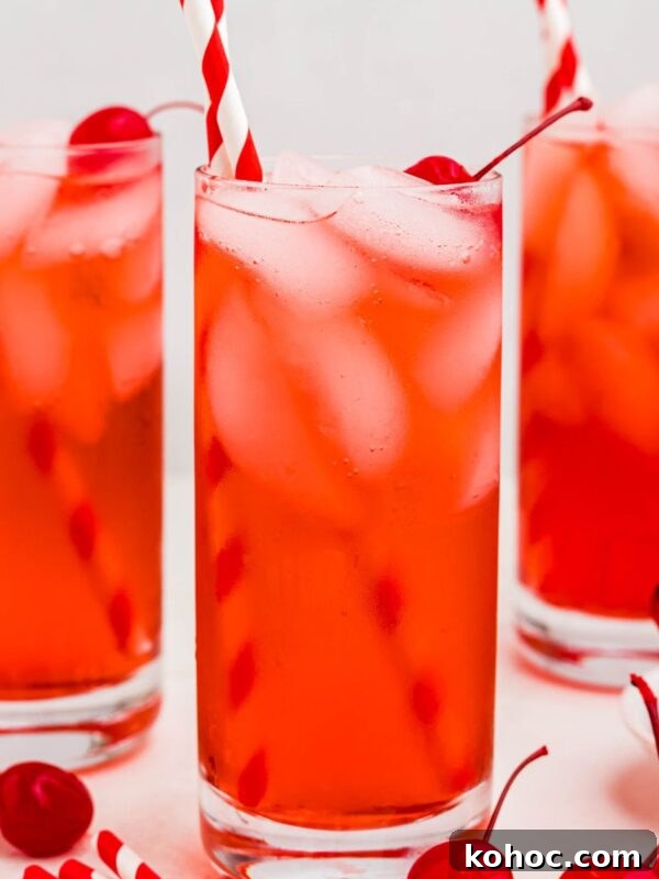 Green Tea Shot Recipe: How to Make the Classic Cocktail 9 Bright red drink in a tall glass with ice and cherries on the table.