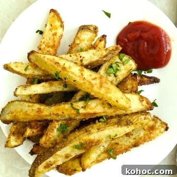 A plate of oven baked french fires with ketchup.