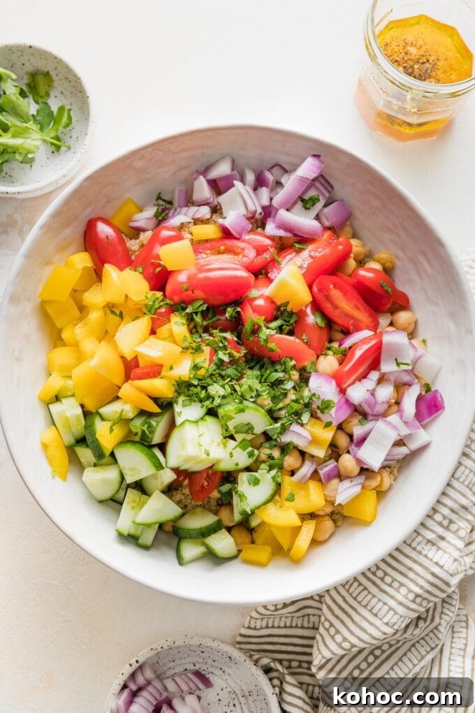 Protein-Packed Quinoa and Chickpea Salad for Meal Prep 5 Chopped pepper, onion, tomatoes, parsley, and cucumber added to bowl with quinoa.