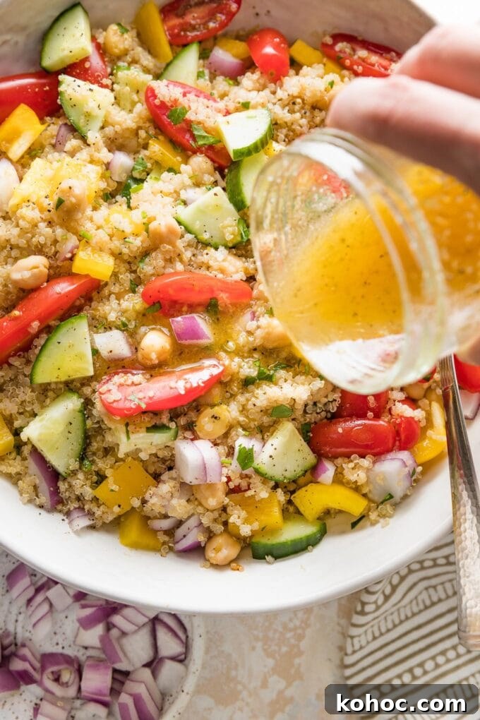Protein-Packed Quinoa and Chickpea Salad for Meal Prep 6 Close up of a homemade lemon dressing being poured over a quinoa chickpea salad.