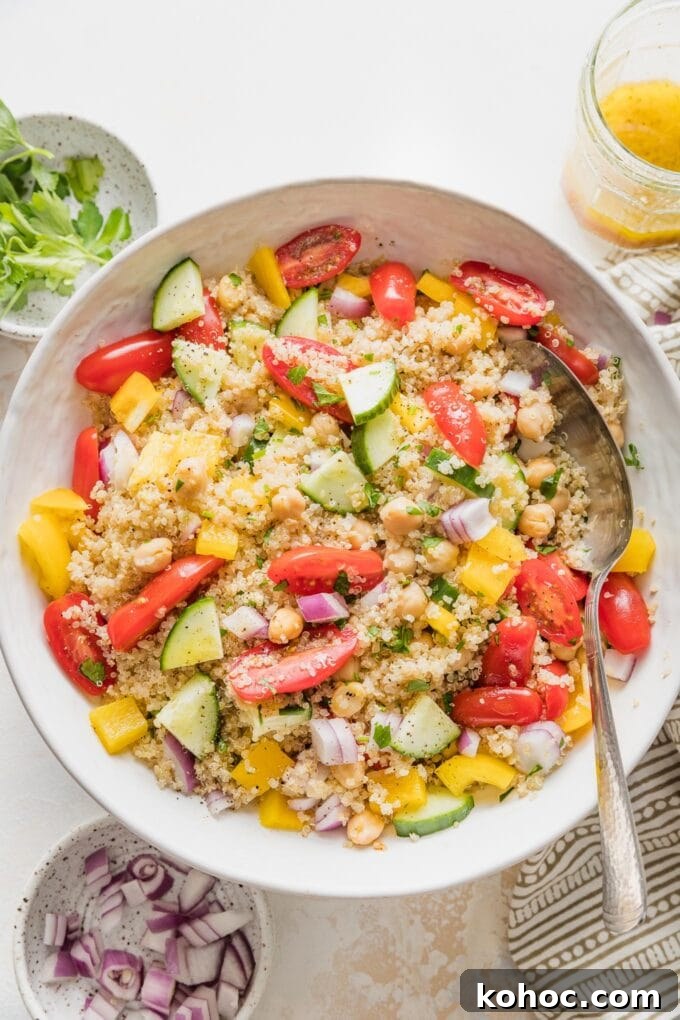 Protein-Packed Quinoa and Chickpea Salad for Meal Prep 7 Serving spoon ready to portion out quinoa chickpea salad.