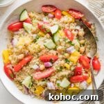 Protein-Packed Quinoa and Chickpea Salad for Meal Prep 8 Bowl full of quinoa chickpea salad with tomatoes, cucumber, and a lemon dressing.