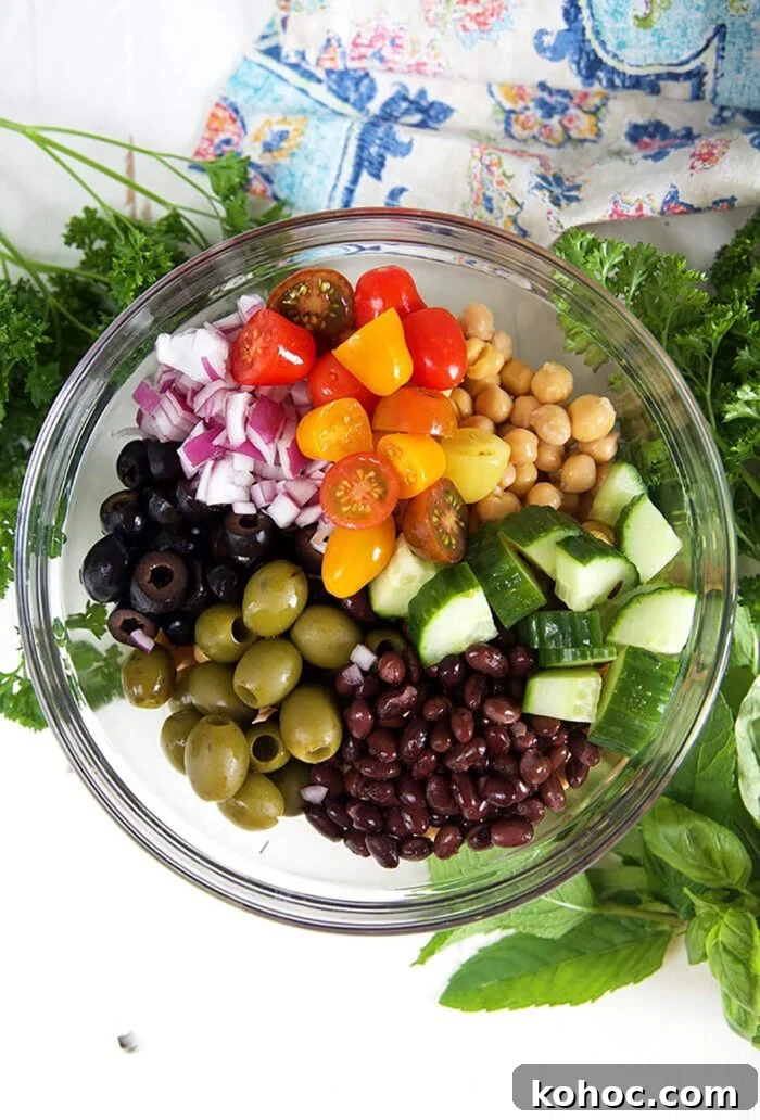 Mediterranean Chickpea Salad with Lemon, Herbs & Feta 6 overhead shot of ingredients for chickpea salad in a glass bowl with herbs.