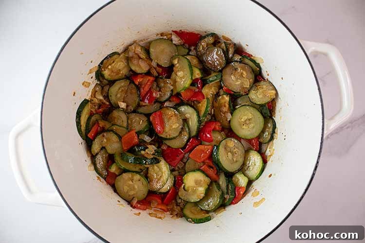 overhead view of ceramic pot with seared zucchini and red peppers