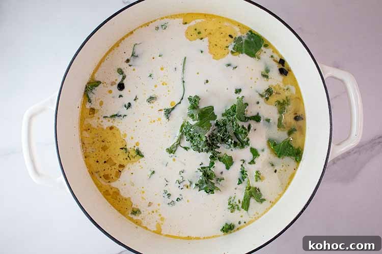overhead view of ceramic soup pot with chicken stock, heavy whipping cream and kale added