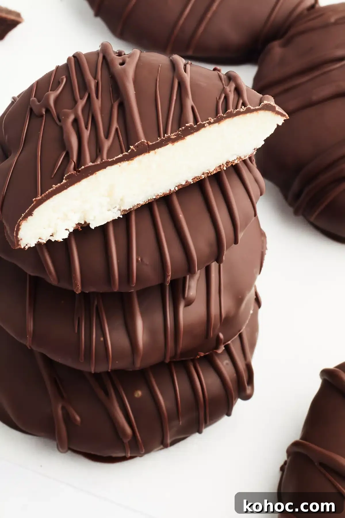 Dairy Free Peppermint Patties @spabettie #dairyfree #vegan #glutenfree #homemade #chocolate A stack of 4 peppermint patties on a white surface, with more sitting next to the stack. The top one on the stack is sliced open to see the bright white peppermint filling.