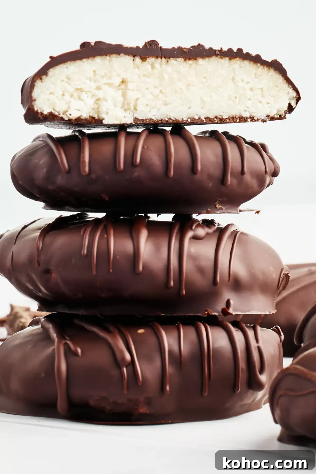 Dairy Free Peppermint Patties @spabettie #dairyfree #vegan #glutenfree #homemade #chocolate Side view of a stack of 4 peppermint patties on a white surface, with more sitting next to the stack. The top one on the stack is sliced open to see the bright white peppermint filling.