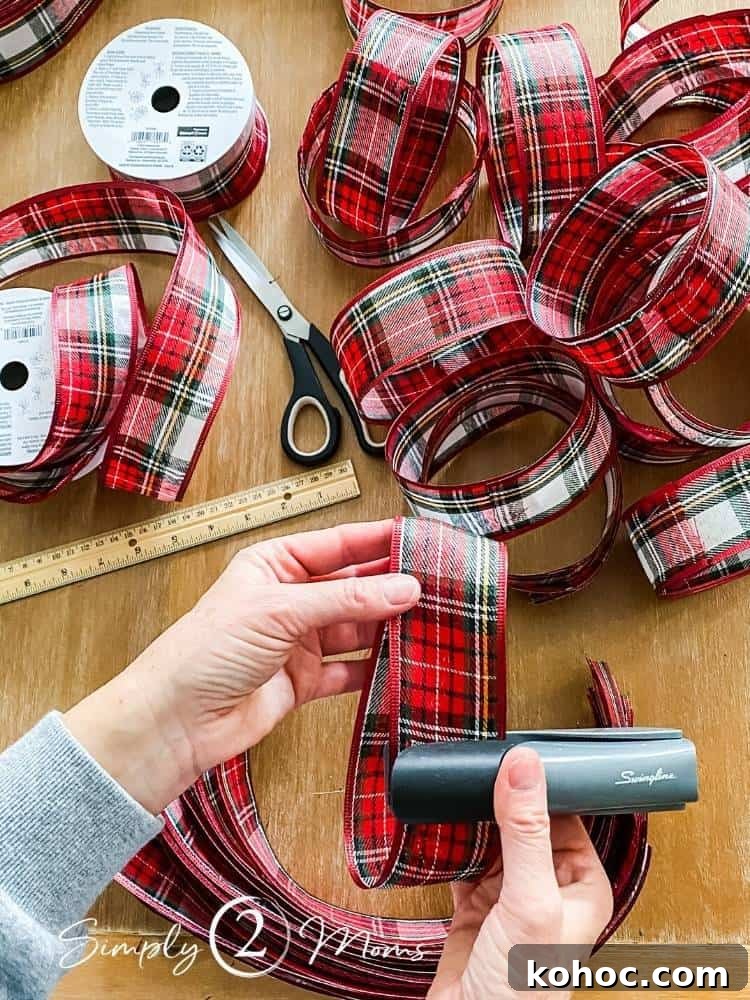 Create Fluffy Christmas Bows in 5 Simple Steps 5 two hands holding ribbon and stapler assembling bow