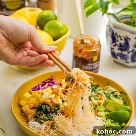 a bowl of spring roll ingredients that someone is taking a bite out of with chopsticks