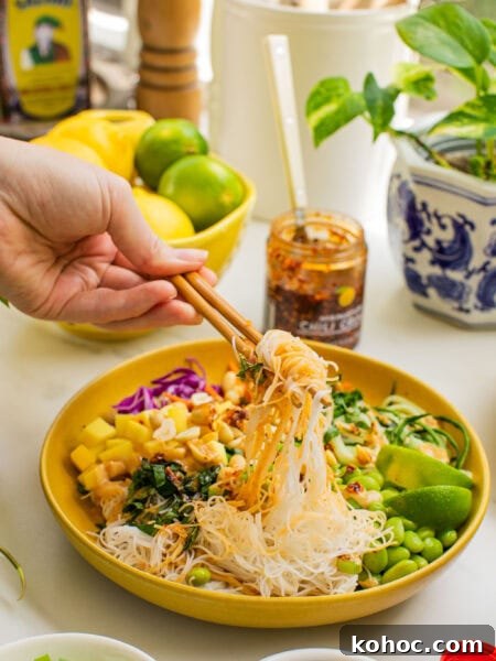 a bowl of spring roll ingredients that someone is taking a bite out of with chopsticks