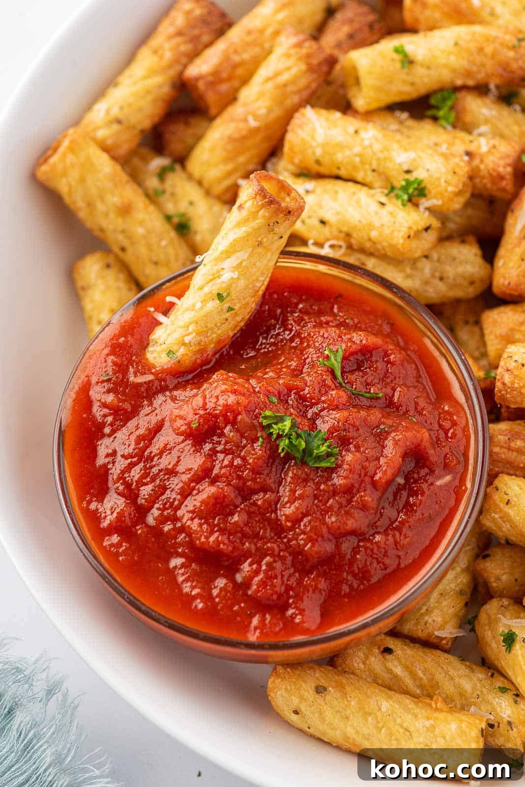 Crispy Air Fryer Pasta Chips Recipe—Quick Snack Idea 6 A plate of fried pasta chips and one fried noodle dipping into marinara sauce.