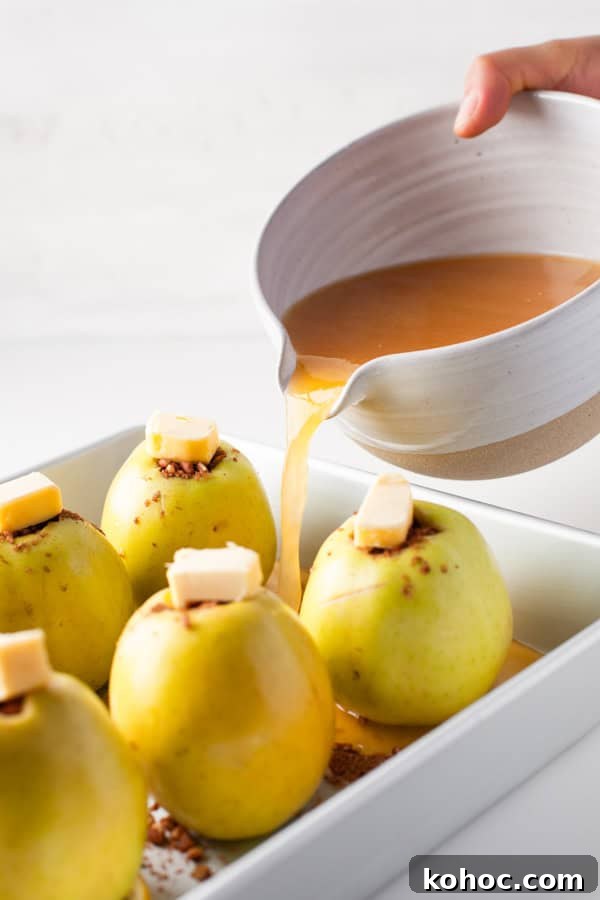 Cinnamon Baked Apples in a dish getting liquid poured into the dish. 