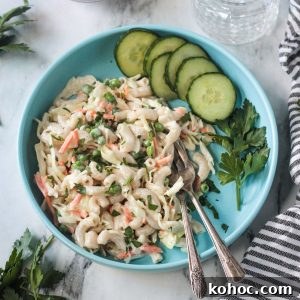 Creamy No-Chop Vegan Macaroni Salad for Quick Meals 14 Vegan Macaroni Salad on a blue plate with two forks and a side of sliced cucumbers.