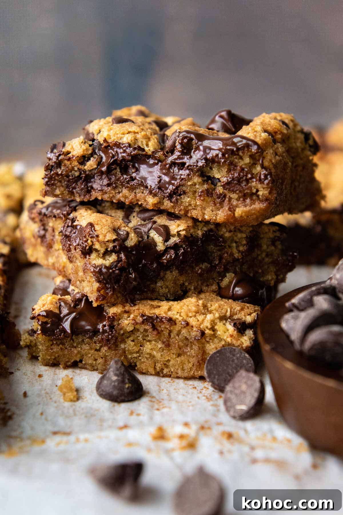 Almond Flour Blondies Recipe – Chewy Gluten-Free Treats 2 a stack of 3 blondies with melted chocolate and chocolate chips scattered around