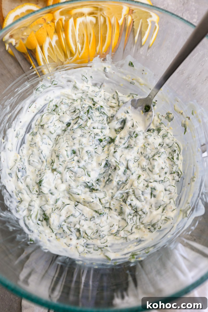 A small clear mixing bowl filled with creamy lemon basil dressing used for chicken salad