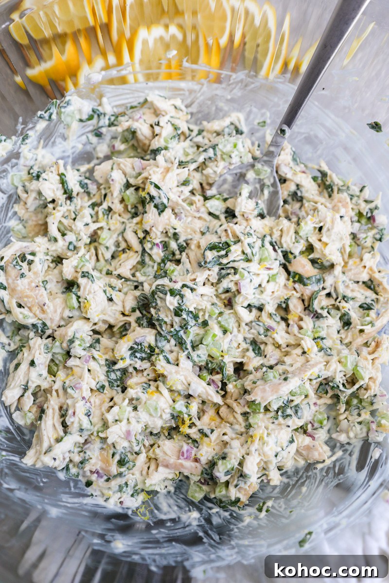 A large clear mixing bowl filled with freshly made lemon basil chicken salad