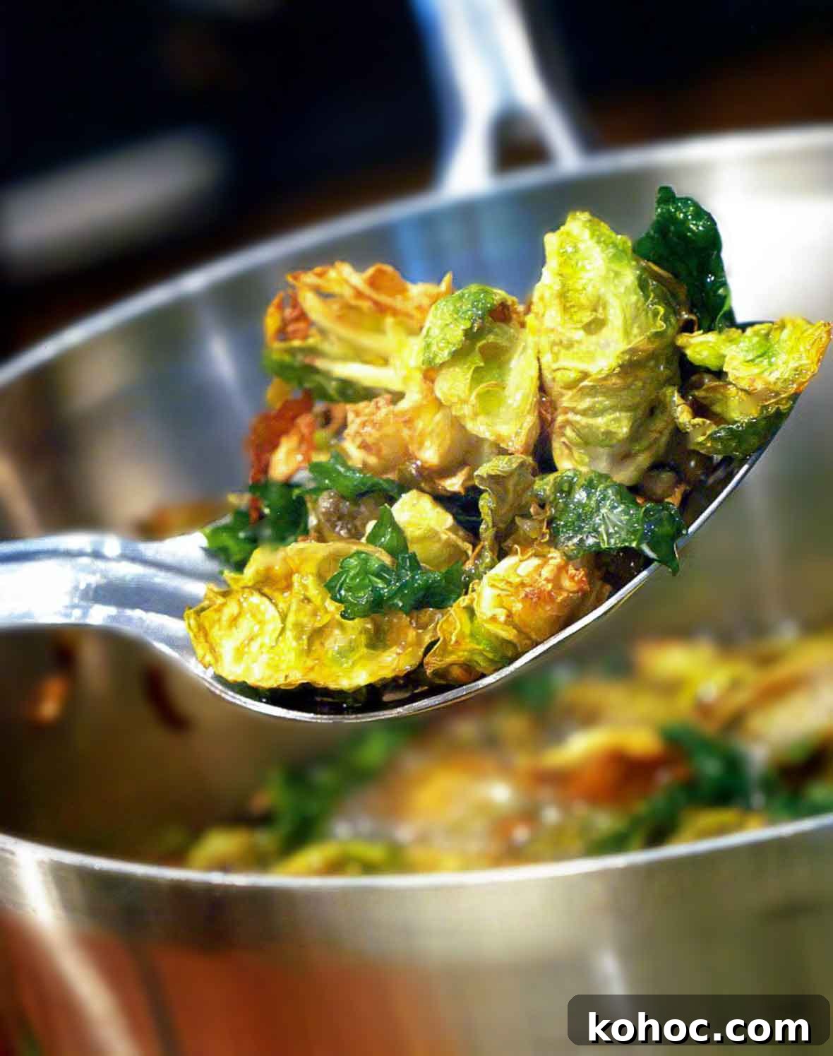 Crispy Fried Brussels Sprouts with Walnuts & Capers 2 A serving spoon of fried Brussels sprouts with walnuts and capers resting over a large metal bowl.