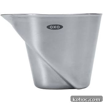 A stainless steel OXO measuring cup with a spout and an angled design, featuring the OXO logo on the front.