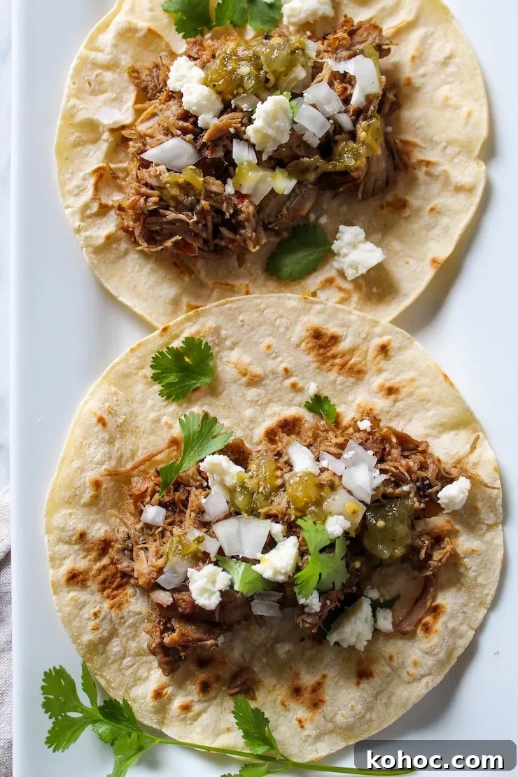 Tacos de carnitas with toppings on tortilla.