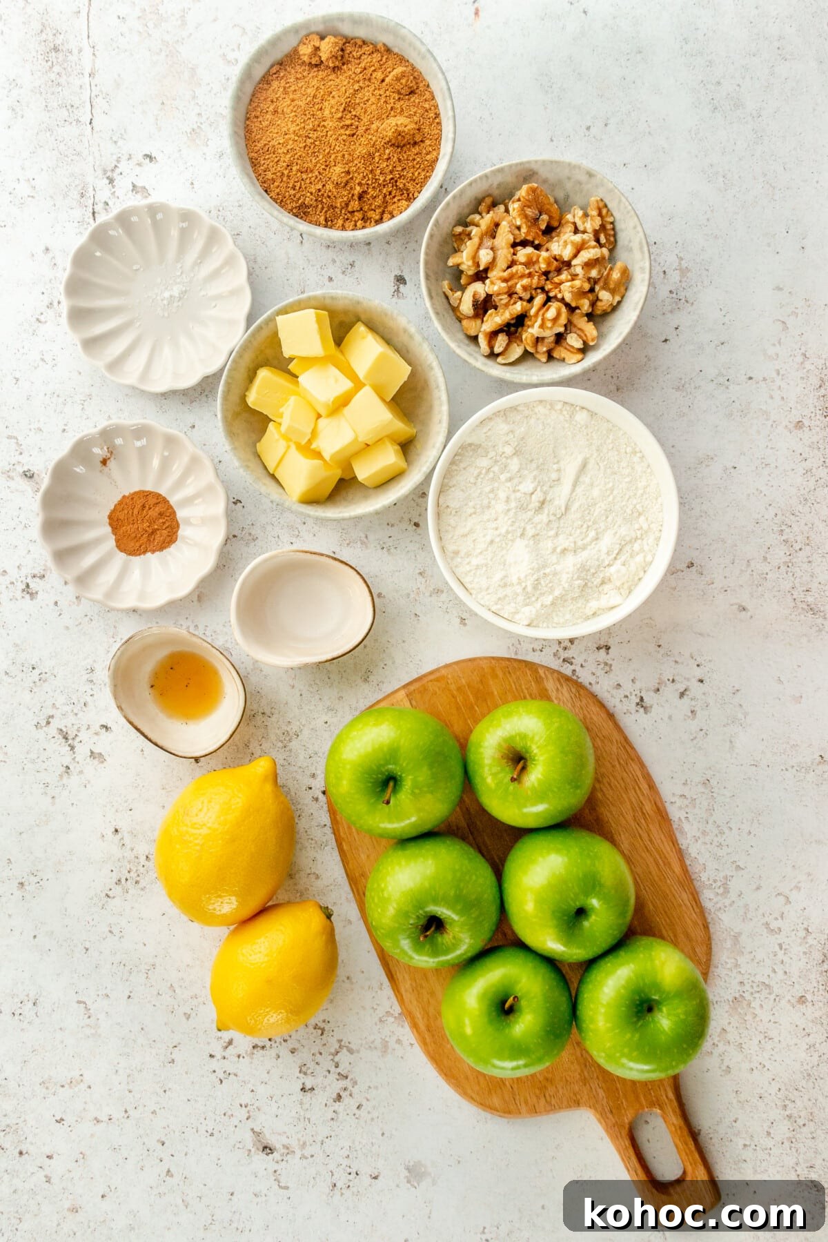 Warm Paleo Apple Crisp with Almond Flour Topping 3 Ingredients for paleo apple crisp sit in a variety of bowls and plates on a light grey surface.