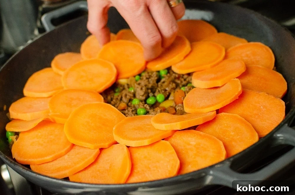 Curried Beef Mince Hotpot Recipe for Comforting Family Dinners 22 Sweet potato slice being placed on top of the mince.