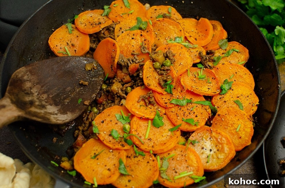 Curried Beef Mince Hotpot Recipe for Comforting Family Dinners 25 Curried mince hotpot all cooked with sprinkled coriander on top being served up with a wooden spoon.
