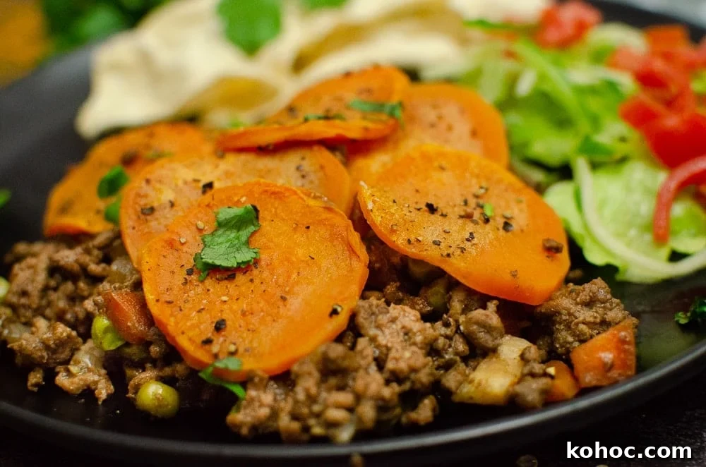 Curried Beef Mince Hotpot Recipe for Comforting Family Dinners 26 Curried mince hotpot served on a black plate with salad and poppadom.