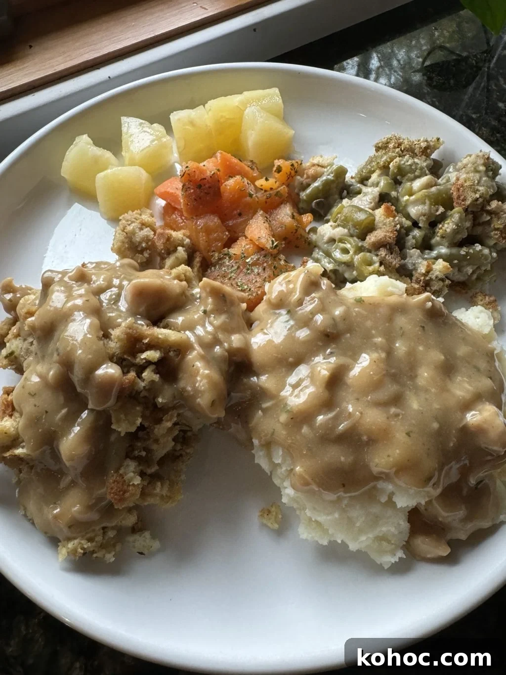 Thanksgiving Dinner Ideas Using Dollar Tree Finds 2 Stuffing, mashed potatoes, and Thanksgiving veggies covered in gravy on a white plate.