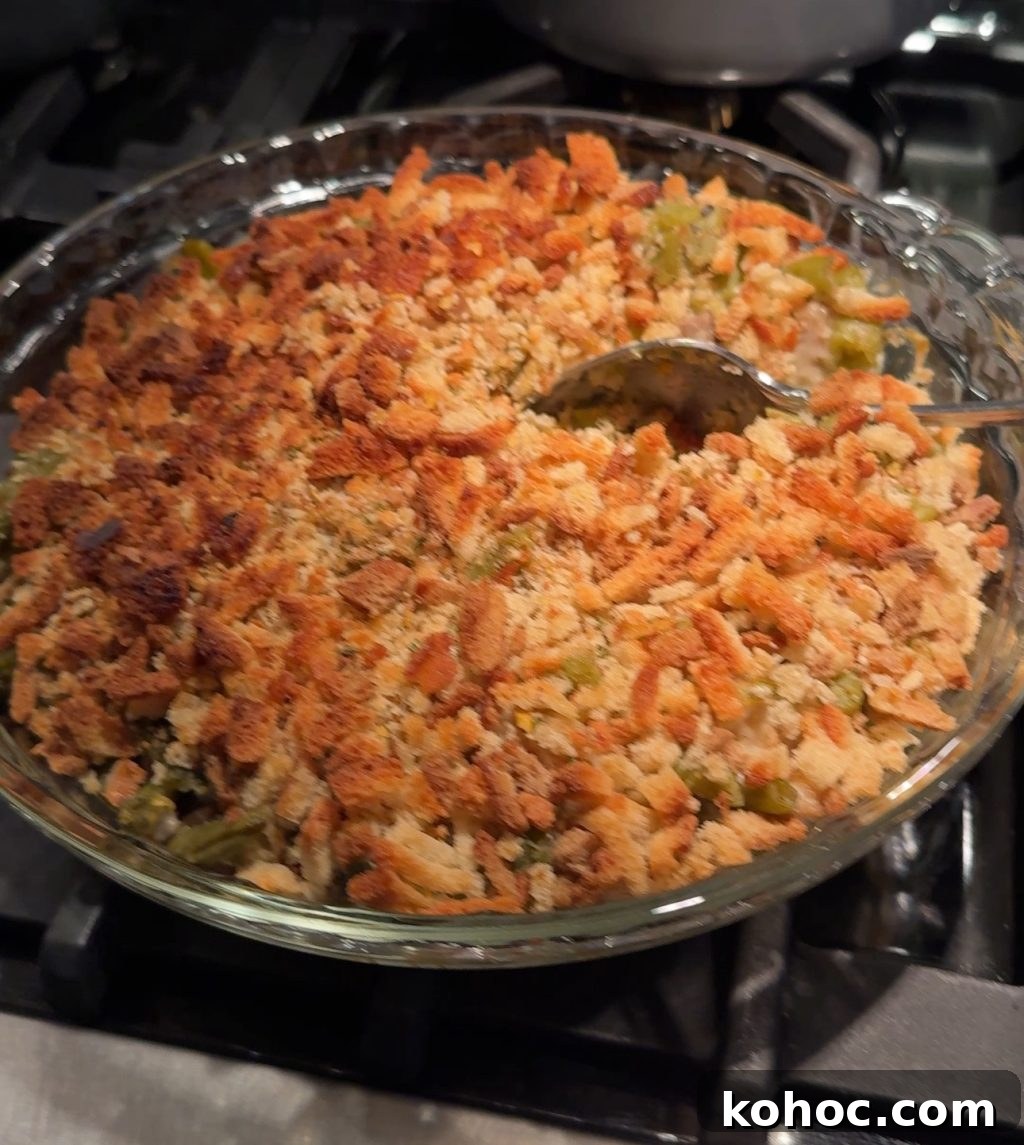 Thanksgiving Dinner Ideas Using Dollar Tree Finds 5 Green bean casserole in a glass dish with a spoon scooping into it.