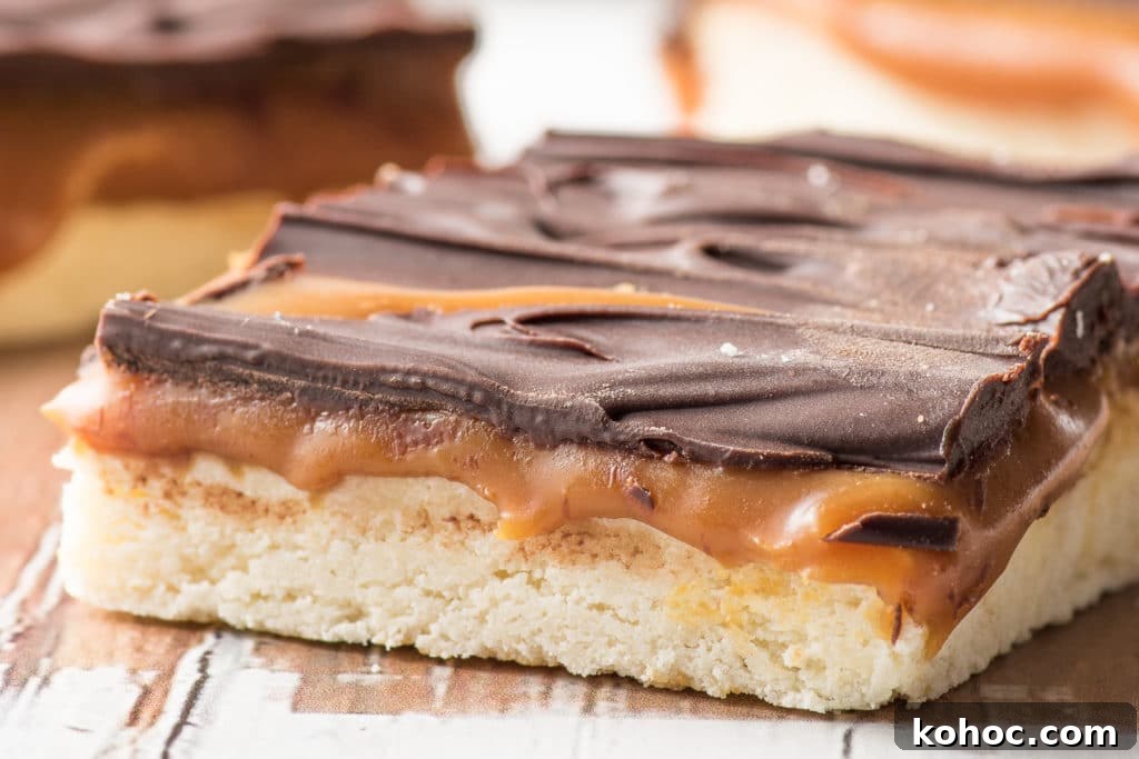 Low-Carb Millionaire Bars: Gooey Sugar-Free Caramel Treat 2 Low carb millionaire bars with gooey caramel filling and dark chocolate crust on a rustic wooden board
