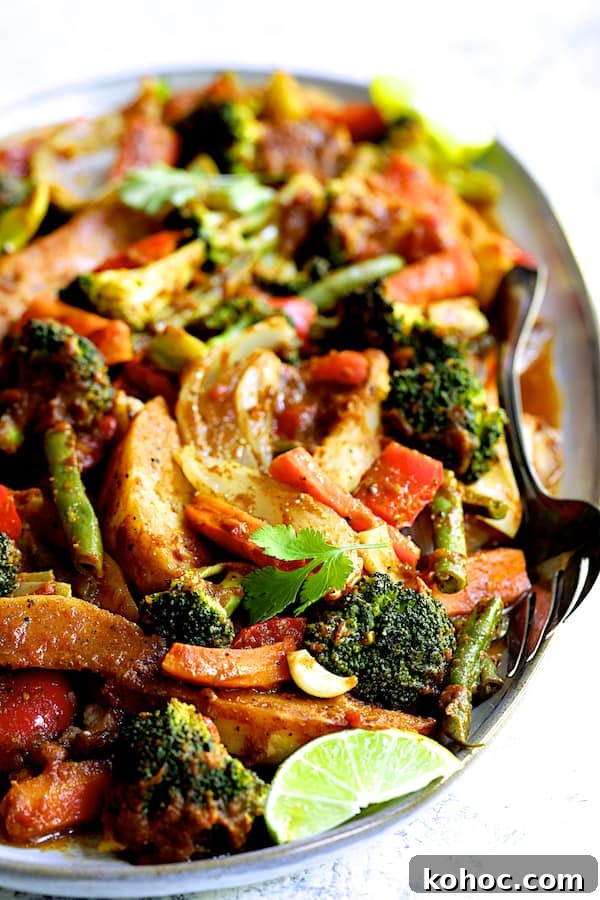 Close-up photo of Curried Roast Vegetables on oval platter with serving fork.
