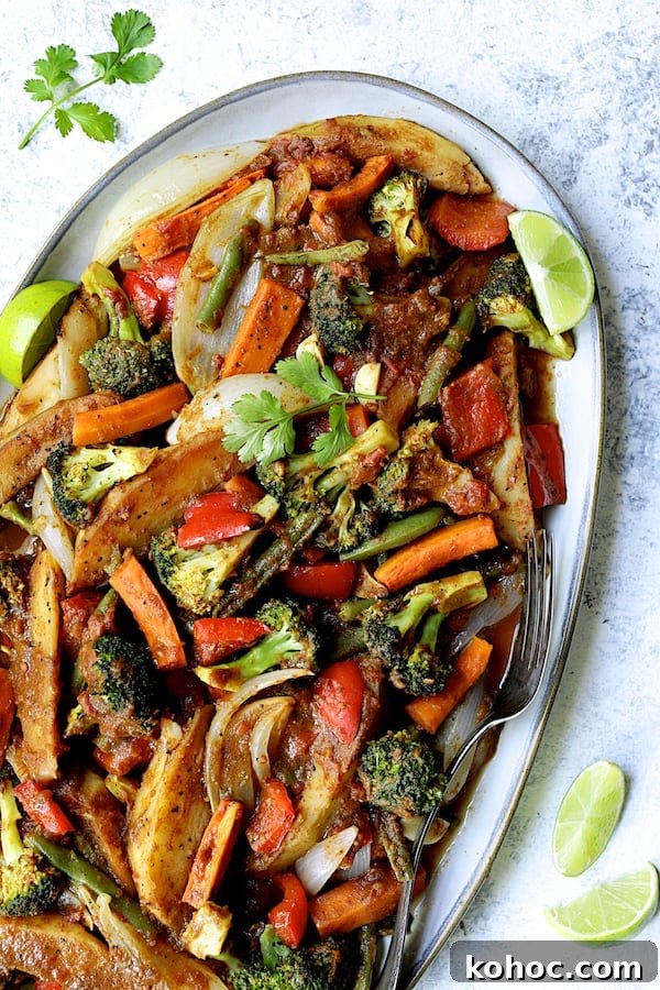 Photo of Curried Roast Vegetables on oval platter with lime wedges and cilantro sprigs.