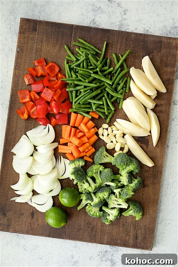 Photo of red bell pepper, green beans potatoes, carrots, onions, garlic, broccoli and limes.