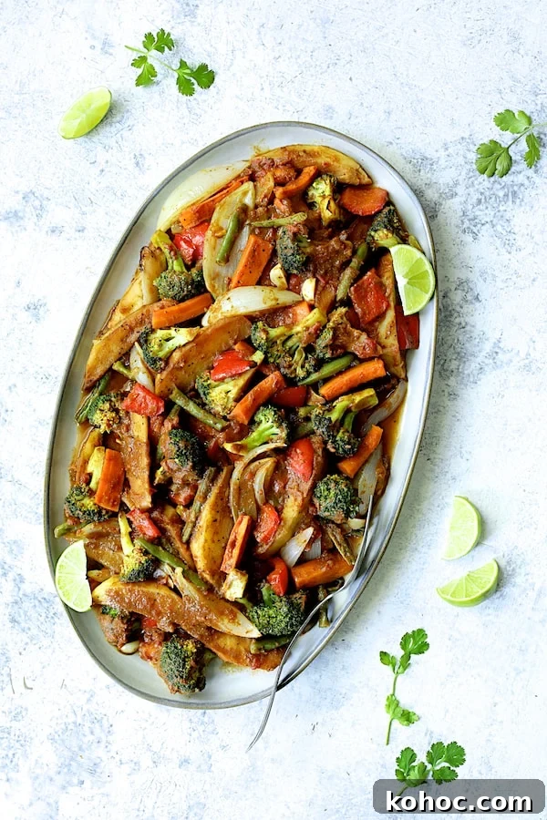 Photo of Curried Roast Vegetables on oval platter garnished with lime wedges and cilantro sprigs.