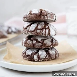 15+ Decadent Chocolate Sourdough Recipes to Try 26 A stack of 4 sourdough chocolate crinkle cookies sitting on a small white plate lined with parchment paper.