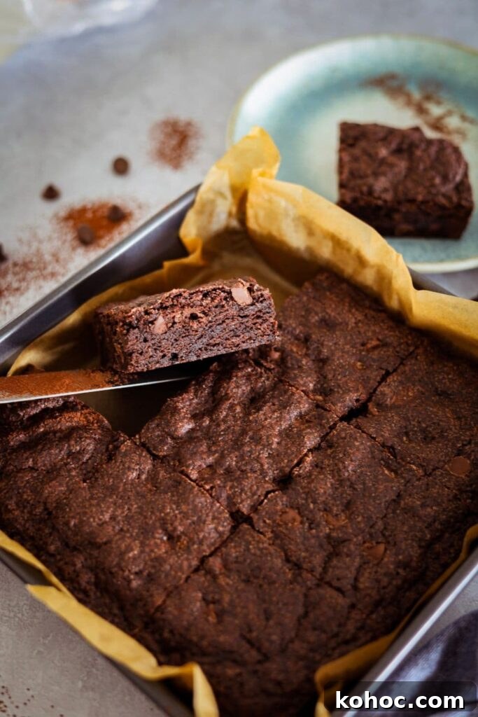 15+ Decadent Chocolate Sourdough Recipes to Try 29 Sourdough chocolate brownie that has been baked and sliced into 9 equal pieces. One of the pieces is being lifted out of the pan so you can see the rich and fudgey interior.