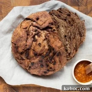 15+ Decadent Chocolate Sourdough Recipes to Try 34 A loaf of chocolate sourdough discard bread on a cutting board, sliced for serving with jam.