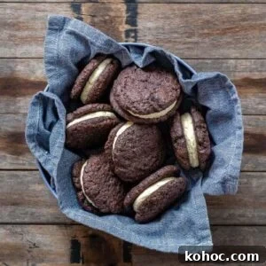 15+ Decadent Chocolate Sourdough Recipes to Try 6 SOURDOUGH CHOCOLATE SANDWICH COOKIES sitting in a blue dish towel on a wooden counter top.