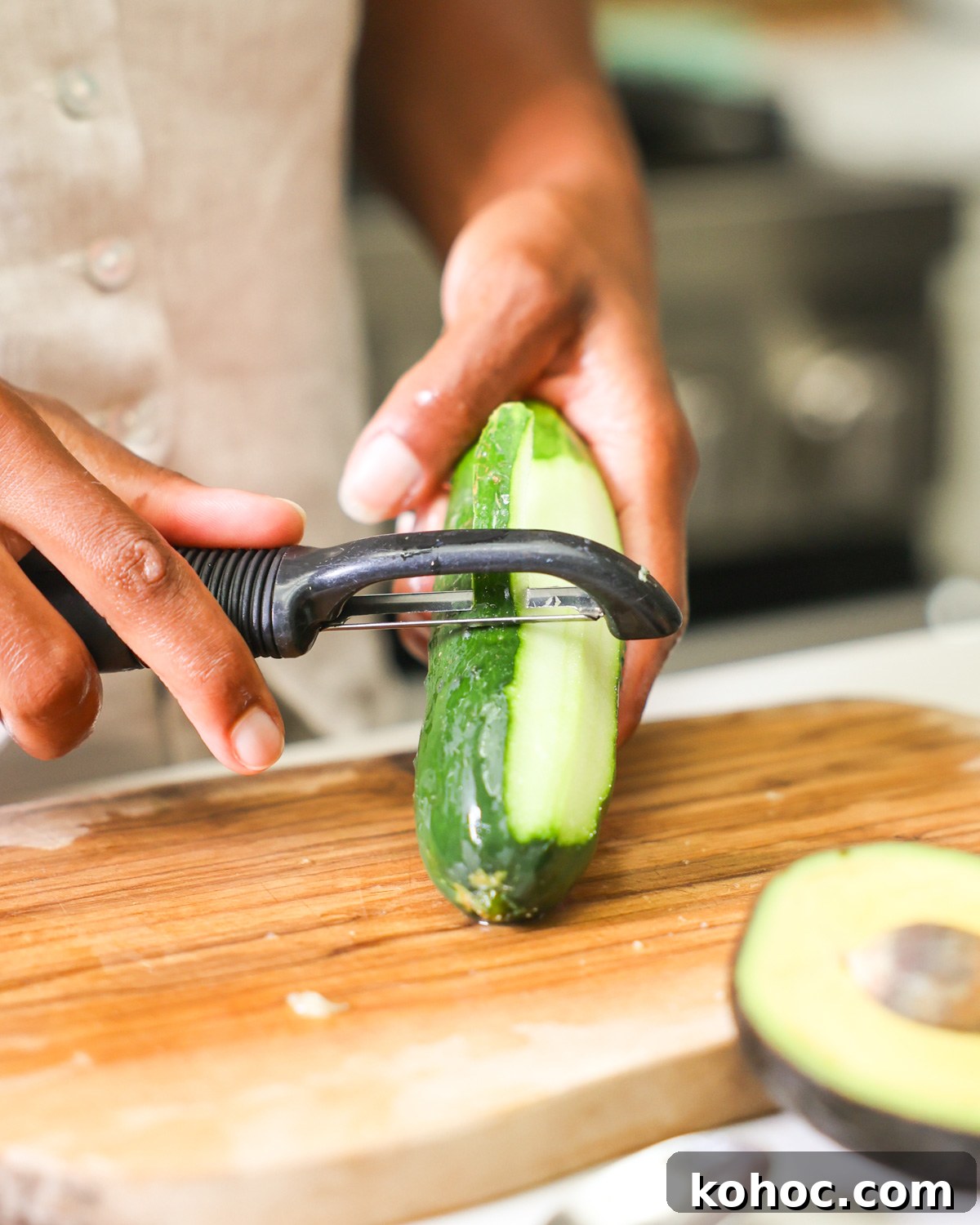 brown hands peeling a cucumber