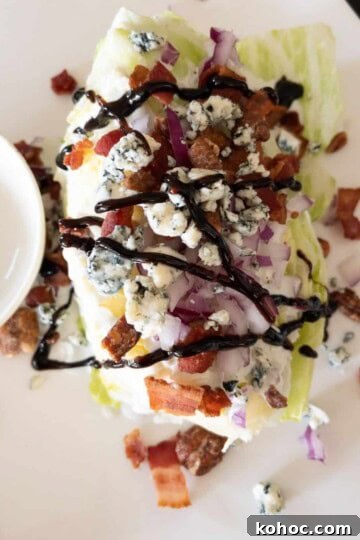 steakhouse wedge salad covered with blue cheese and balsamic glaze on white plate
