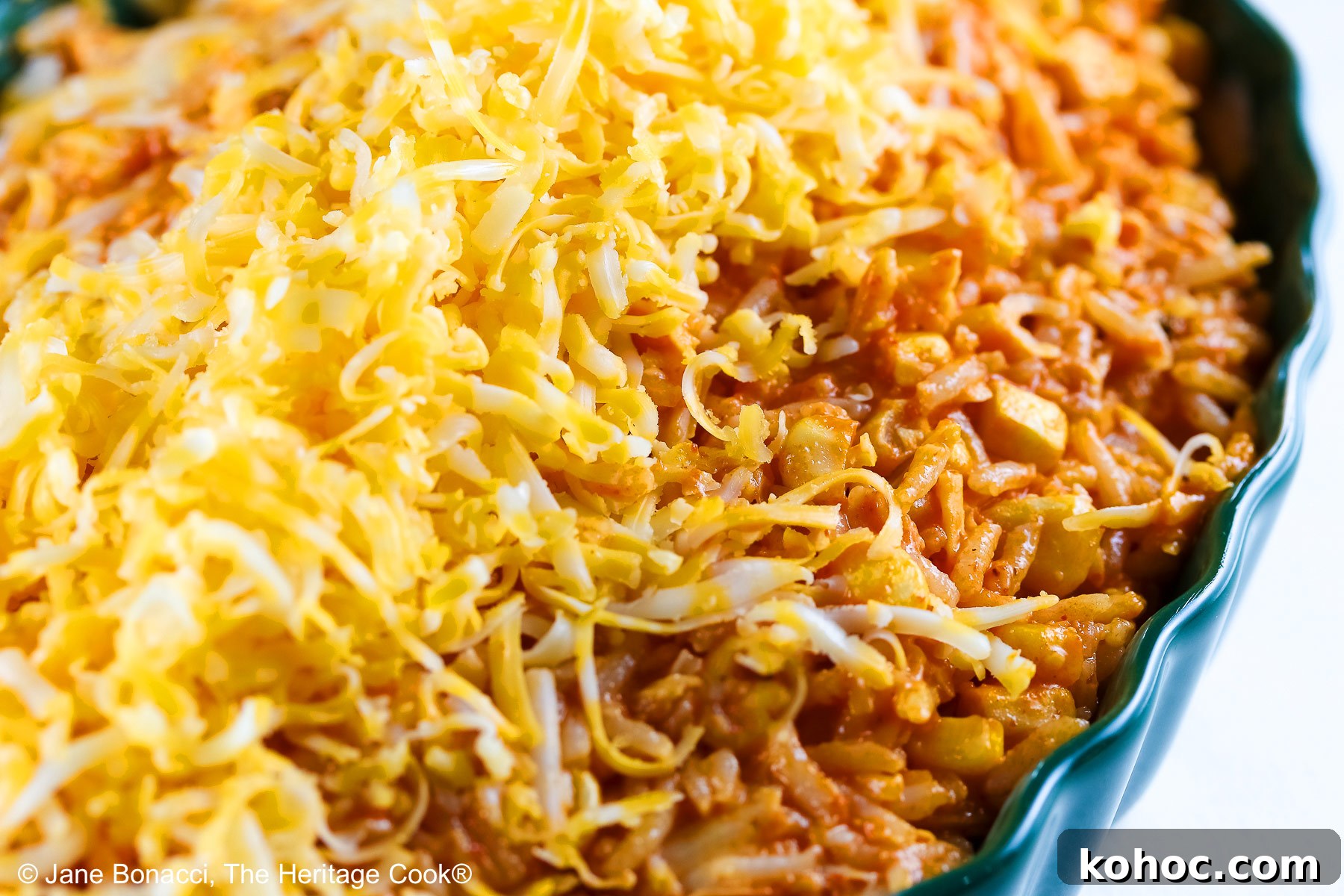Bowl of cooked rice with shredded cheese on top ready for melting.
