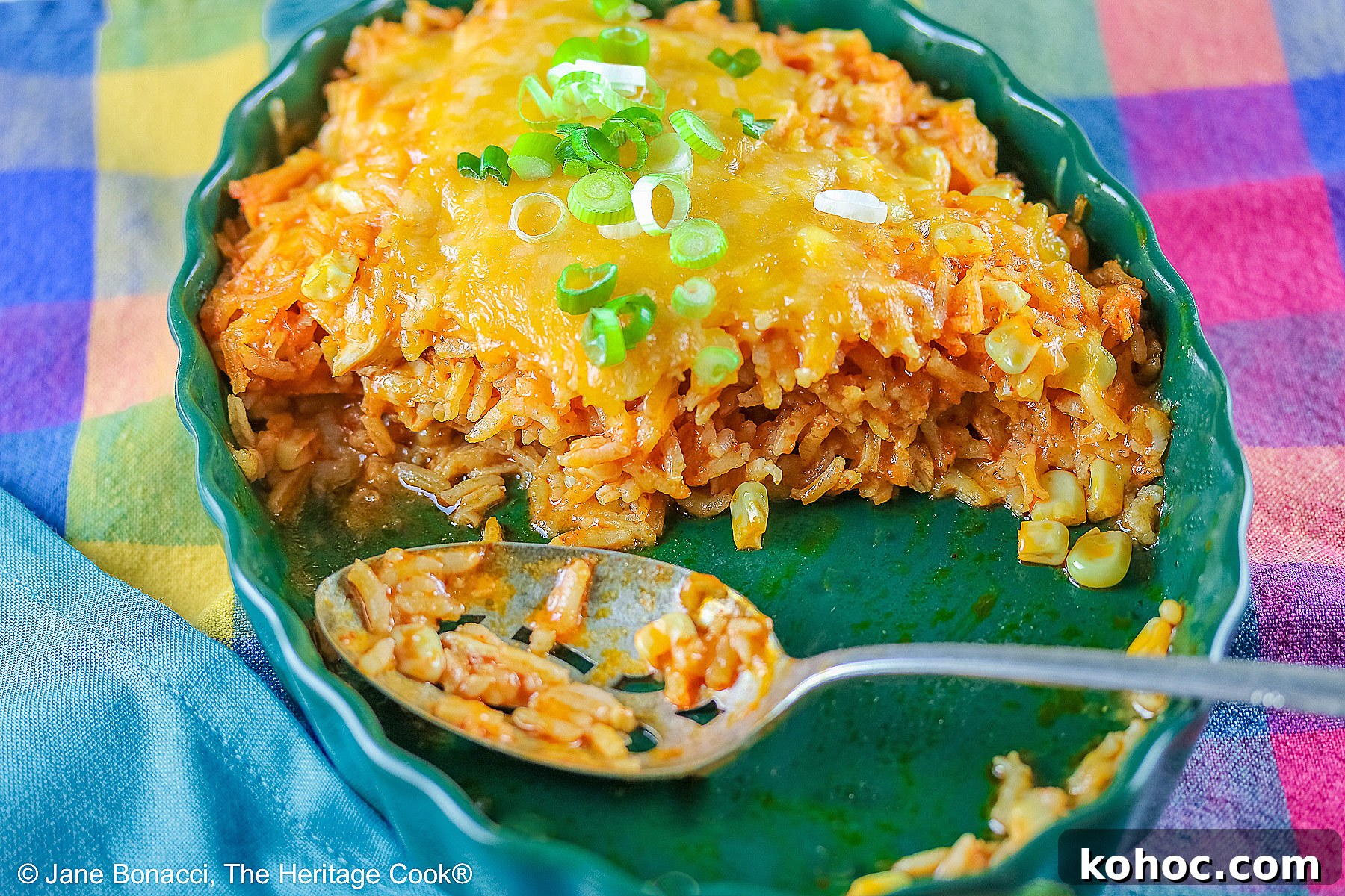 Dish of finished rice half empty with a spoon sitting in the dish. Half has been served.