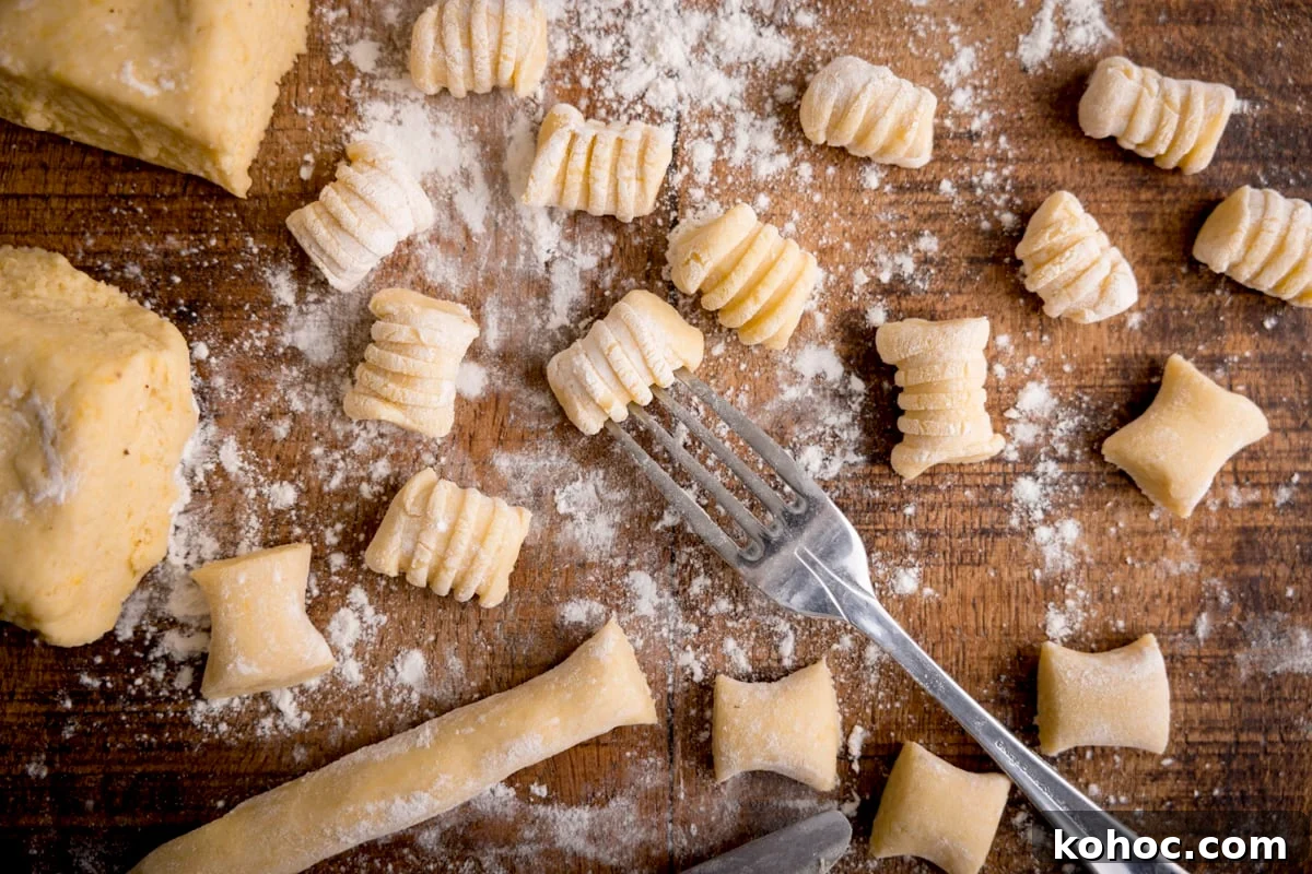Wide image of Gnocchi being cut and shaped on a wooden board.