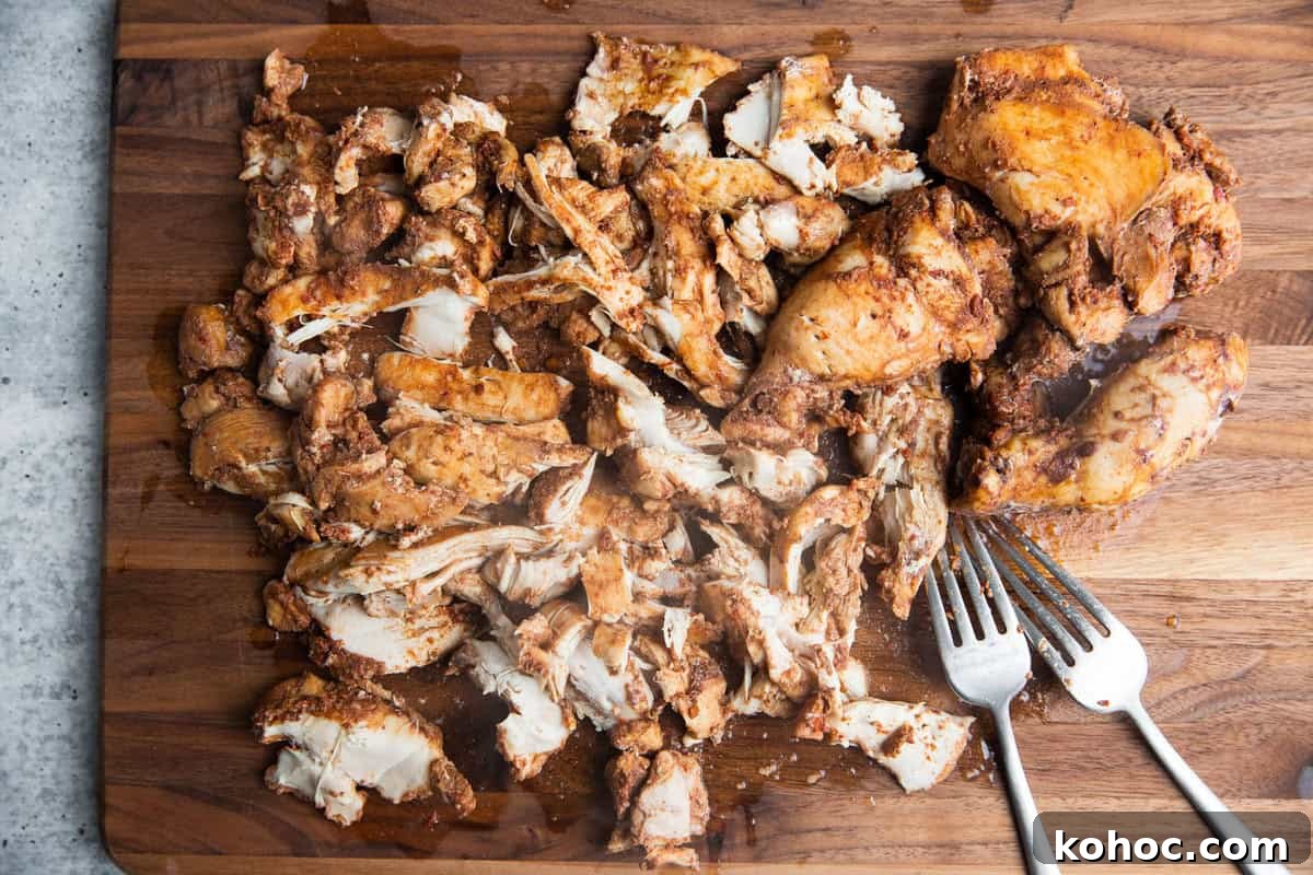 Slow-Cooker Shredded Chipotle Chicken Recipe for Tacos & Bowls 8 chicken shredded on a cutting board with two forks