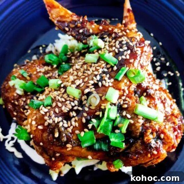 Crispy Oven-Baked Asian-Style Chicken Wings for Game Night 11 Crispy Baked Asian Chicken Wings on a plate with chopped green onions and baked sesame seeds for garnish.