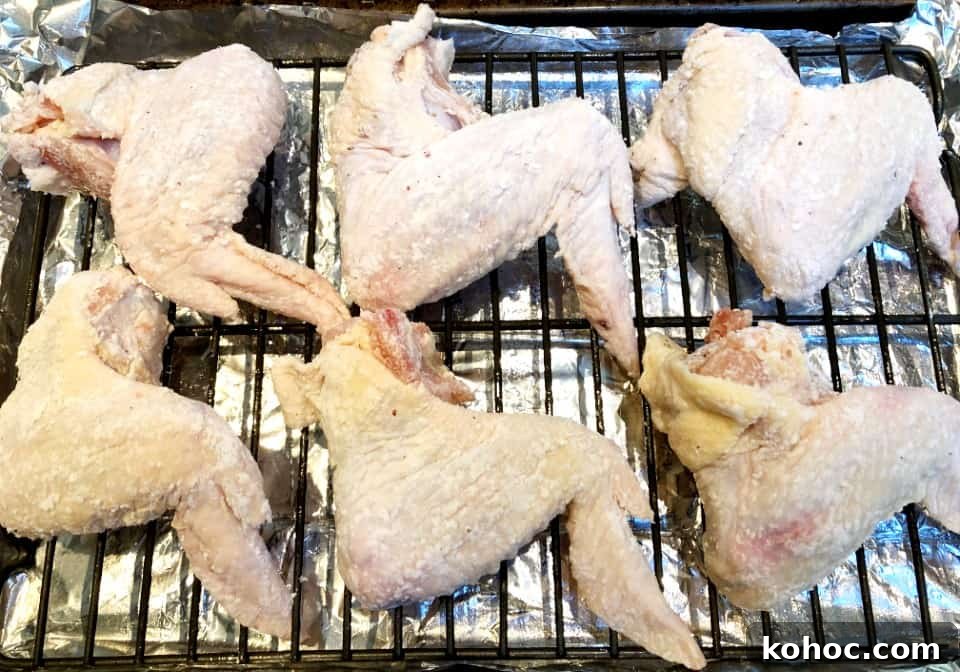Crispy Oven-Baked Asian-Style Chicken Wings for Game Night 4 raw chicken wings on a rack before baking.