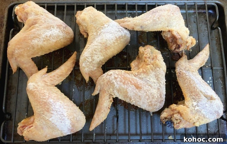 Crispy Oven-Baked Asian-Style Chicken Wings for Game Night 5 chicken wings coated in baking powder after baking.