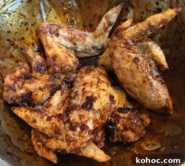Crispy Oven-Baked Asian-Style Chicken Wings for Game Night 8 baked chicken wings in a bowl with sauce.
